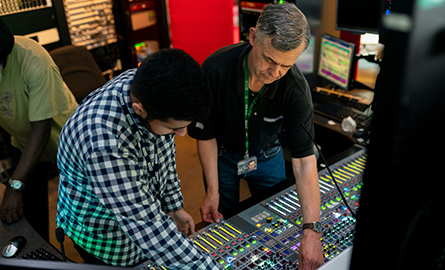 Broadcast engineer and apprentice work in a studio