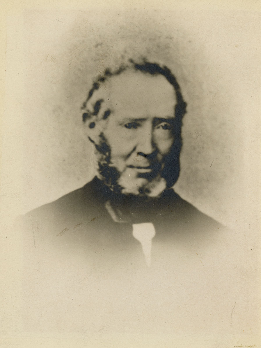 Historic image of an adult white male from the 1800s wearing a formal jacket and shirt.
