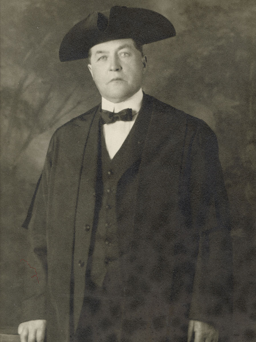 Historic image of an adult white male from the early 1900s wearing a formal jacket and shirt.