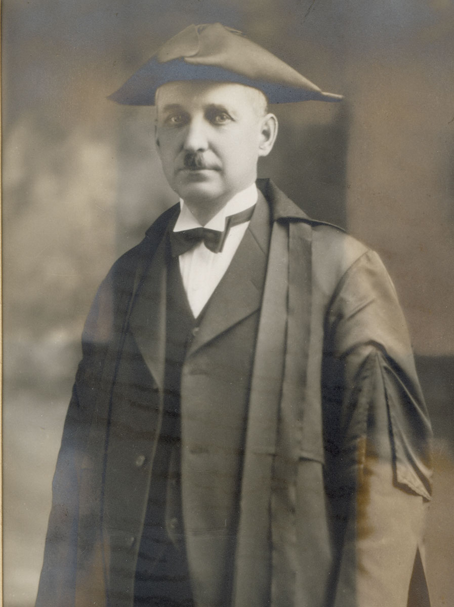 Historic image of an adult white male from the early 1900s wearing a formal jacket and shirt.