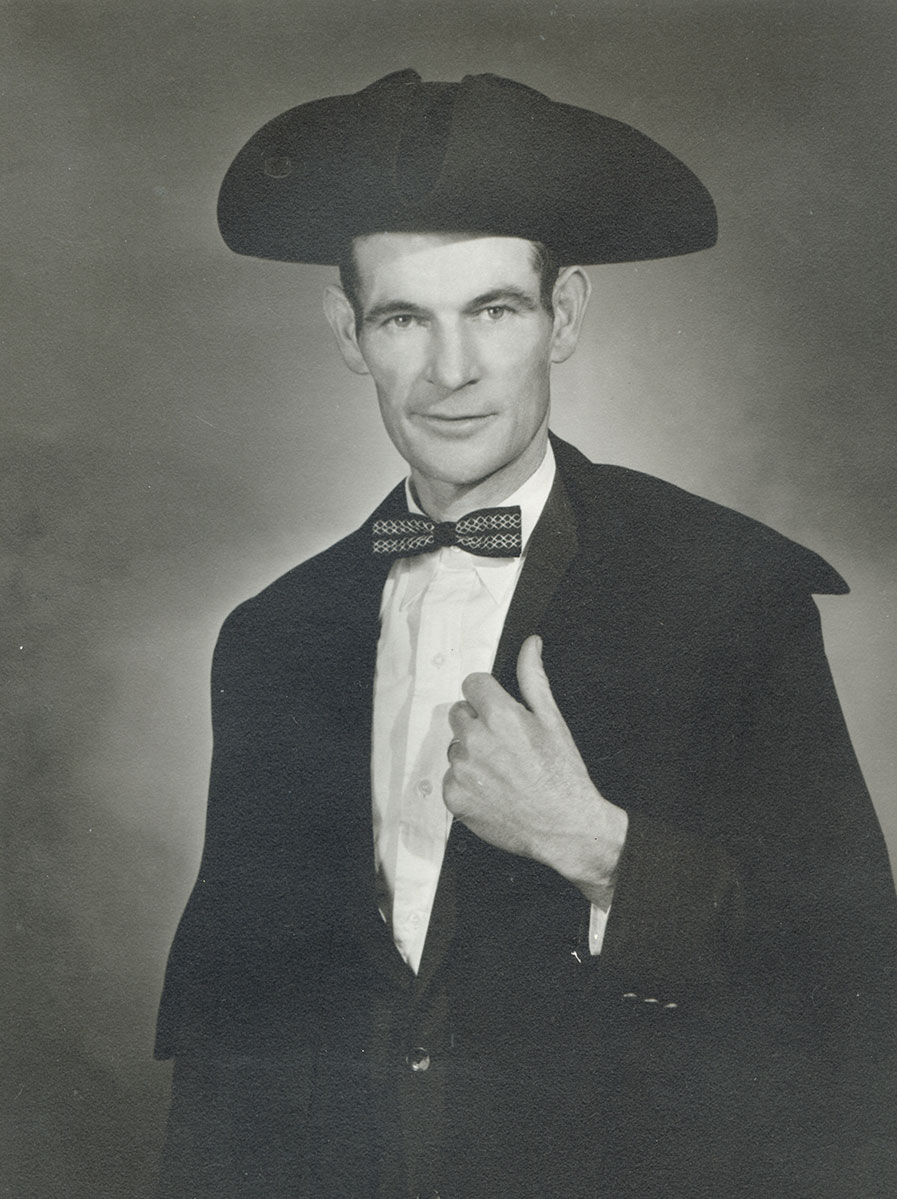 Black and white photo of white male in wardens cap and gown