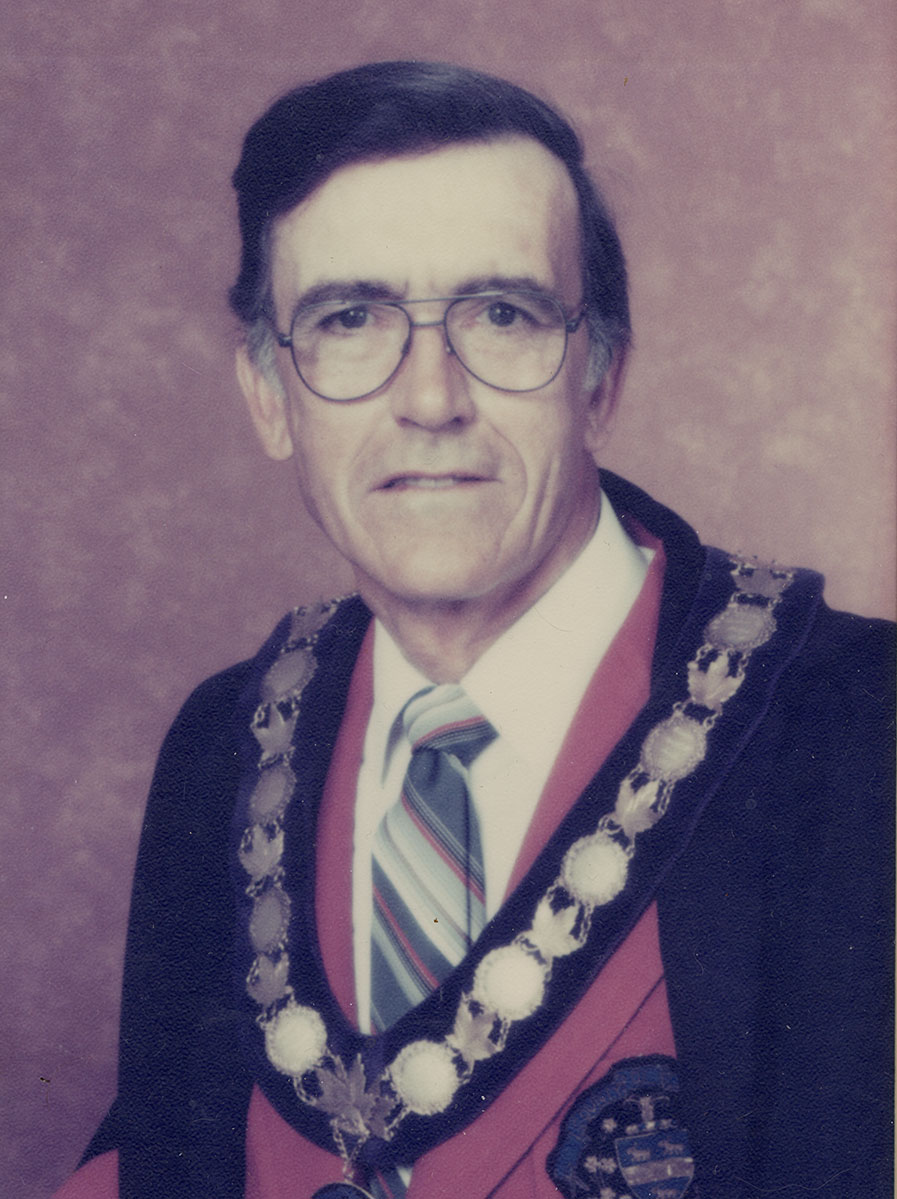Photo of man in a suit and warden medal.