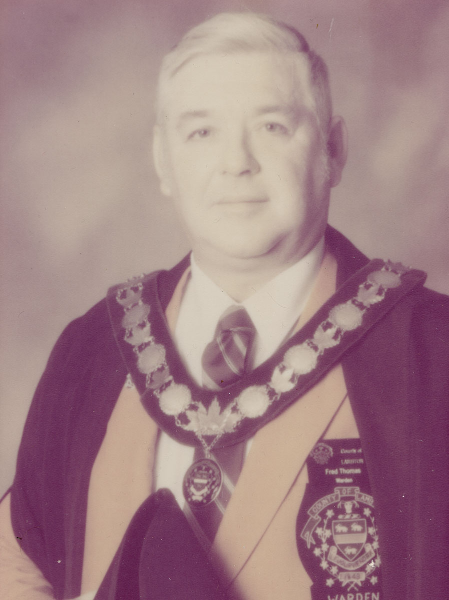 Photo of man in a suit and warden medal.