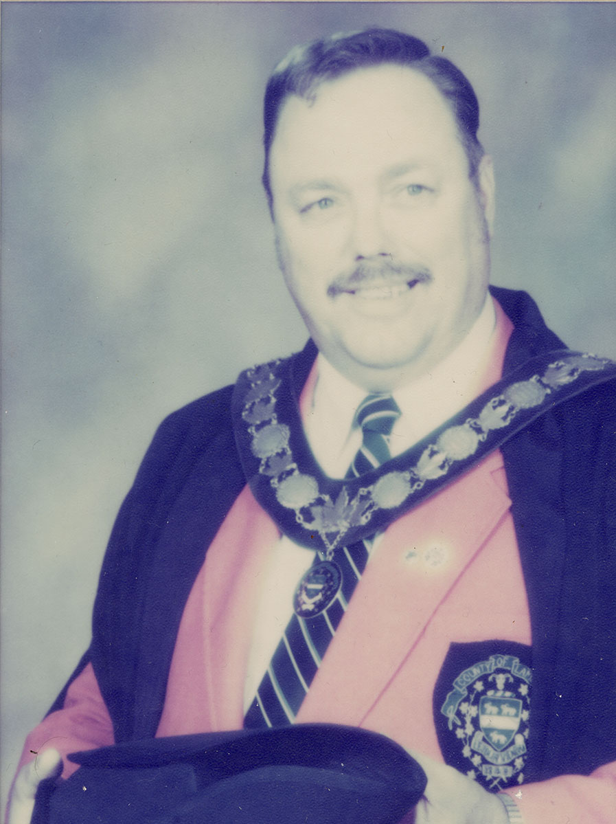 Photo of man in a suit and warden medal.