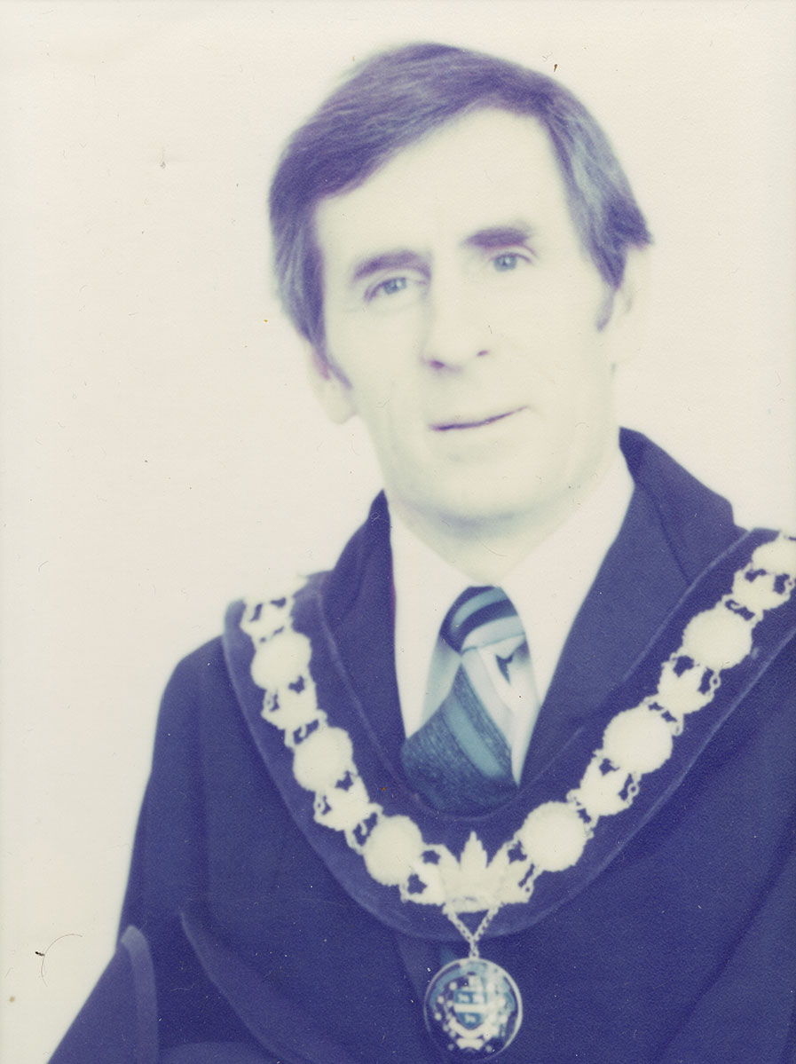 Photo of man in a suit and warden medal.