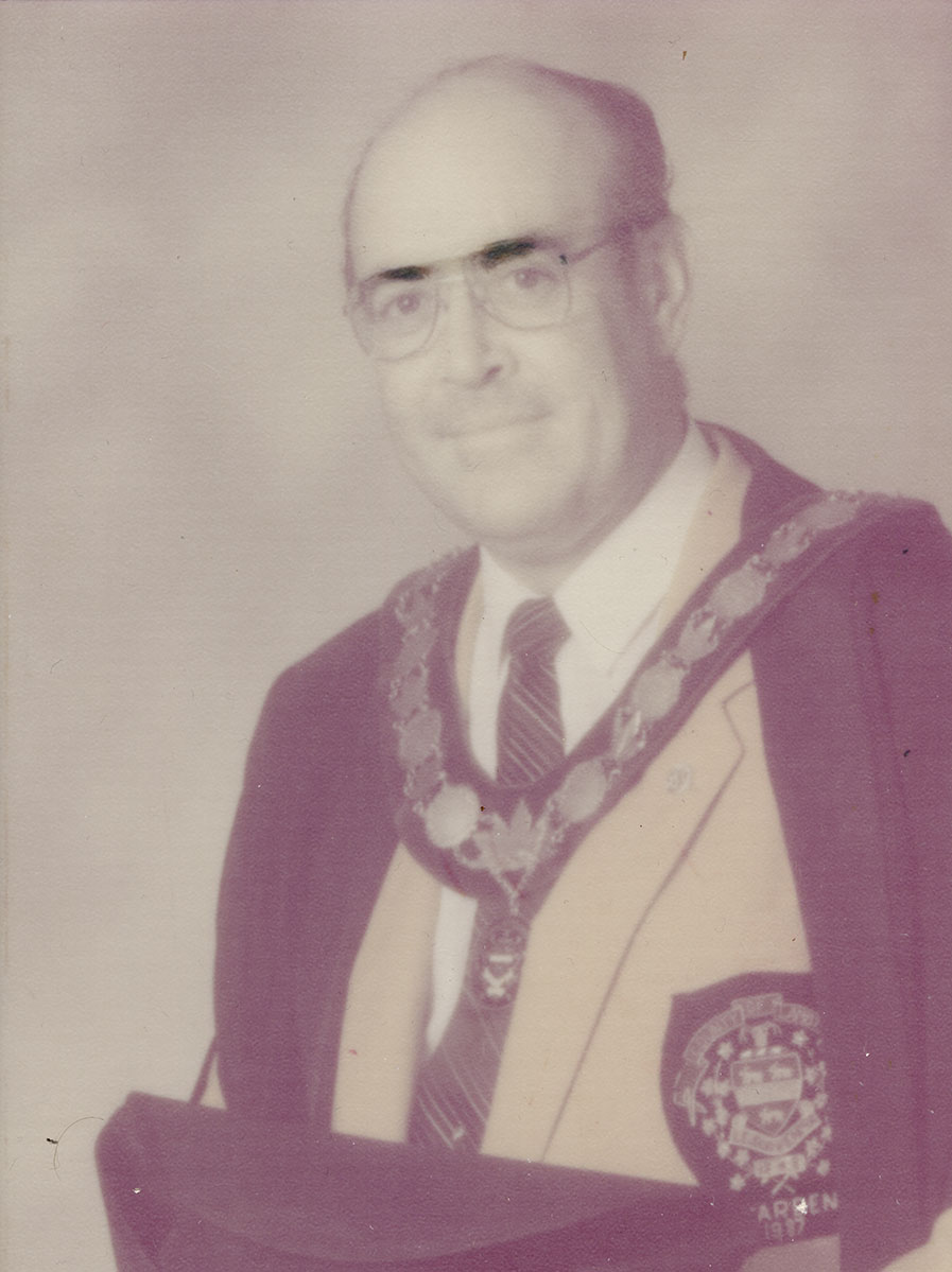 Photo of man in a suit and warden medal.