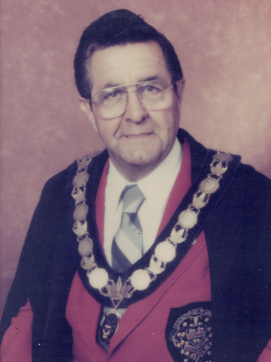Photo of man in a suit and warden medal.