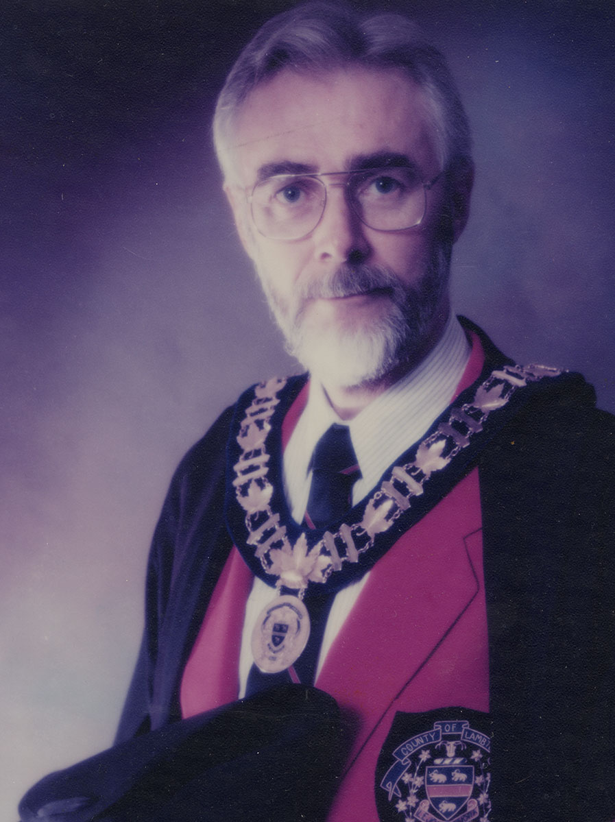Photo of man in a suit and warden medal.