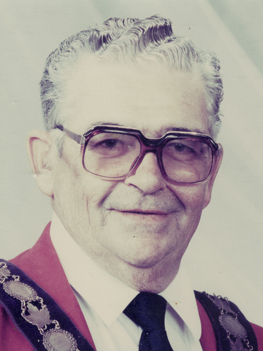 Photo of man in a suit and warden medal.