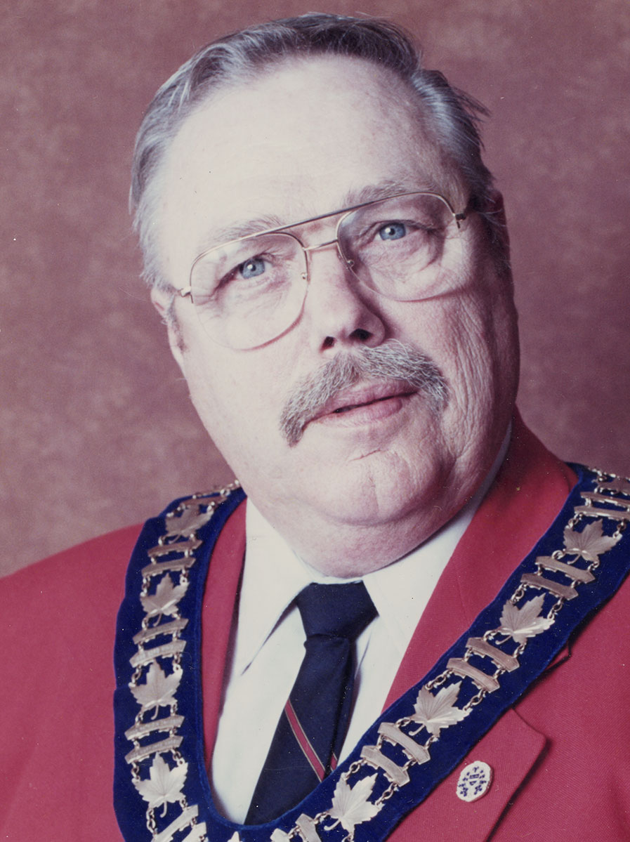 Photo of man in a suit and warden medal.