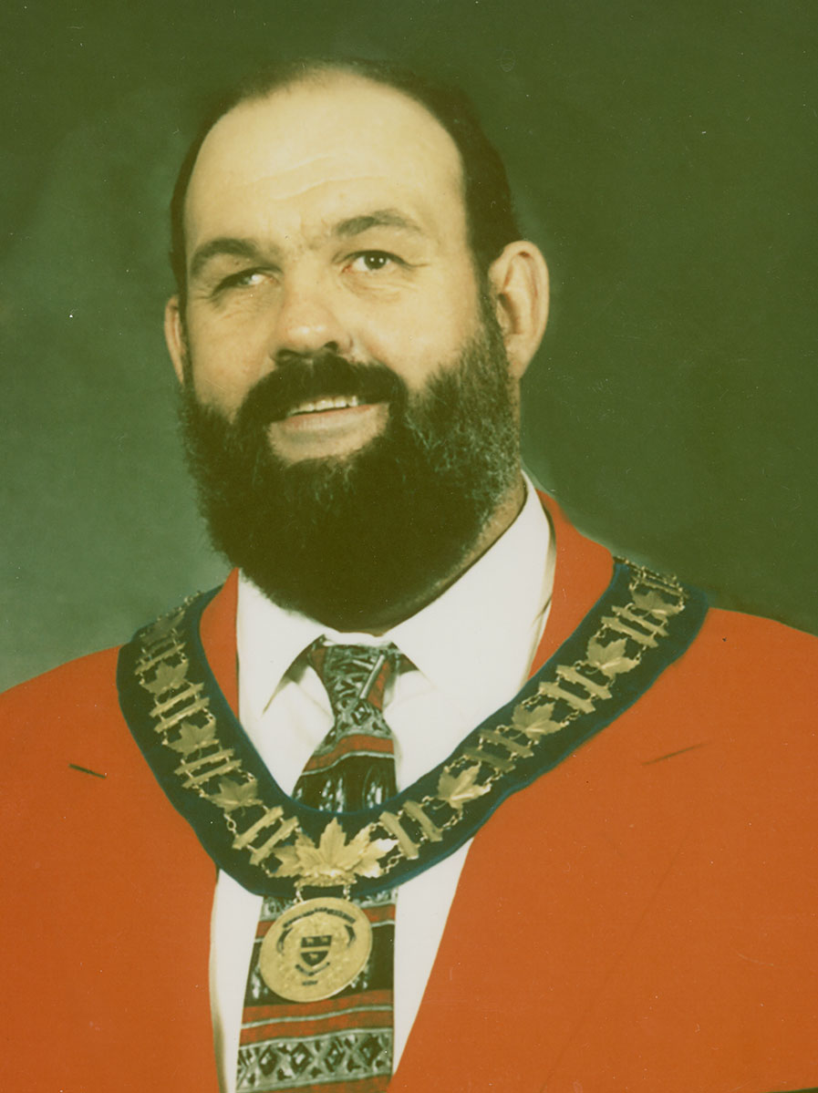 Photo of man in a suit and warden medal.