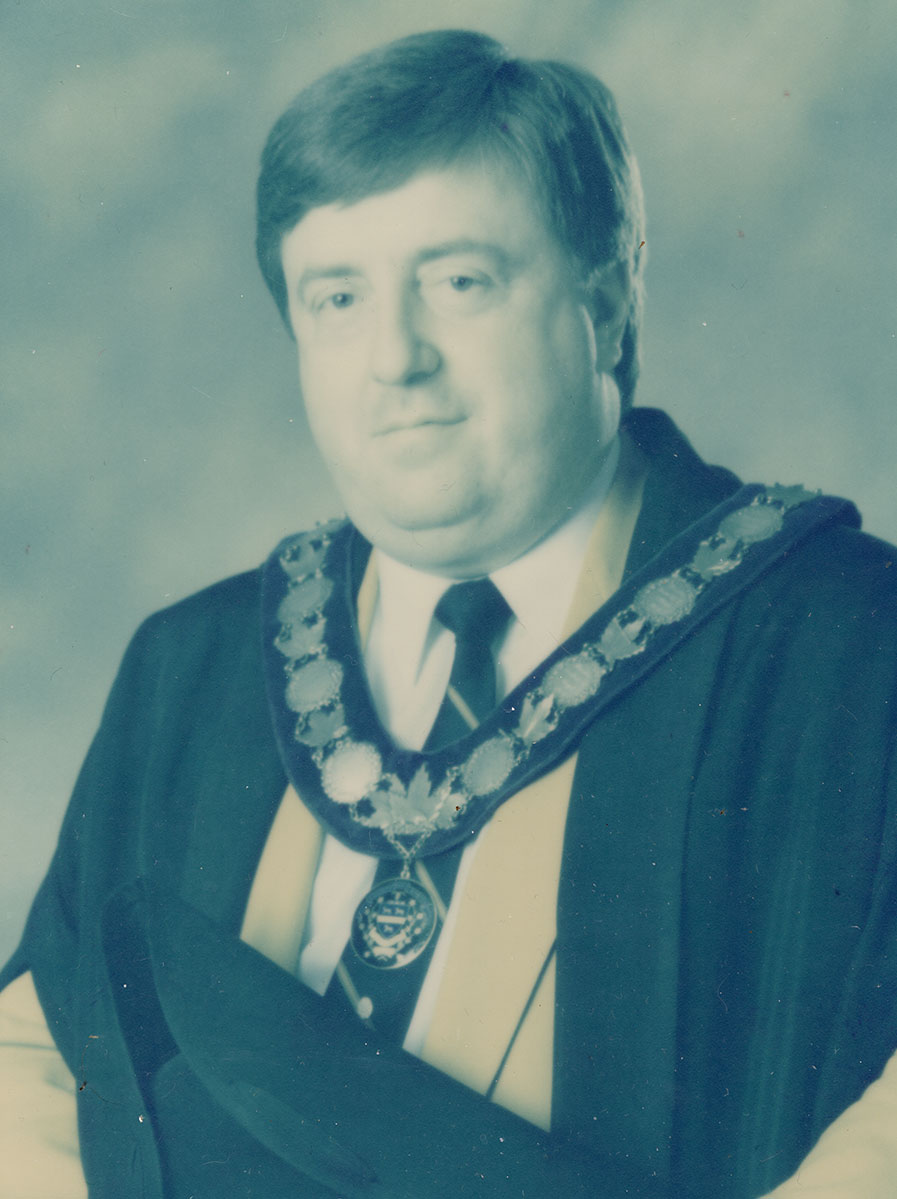 Photo of man in a suit and warden medal.