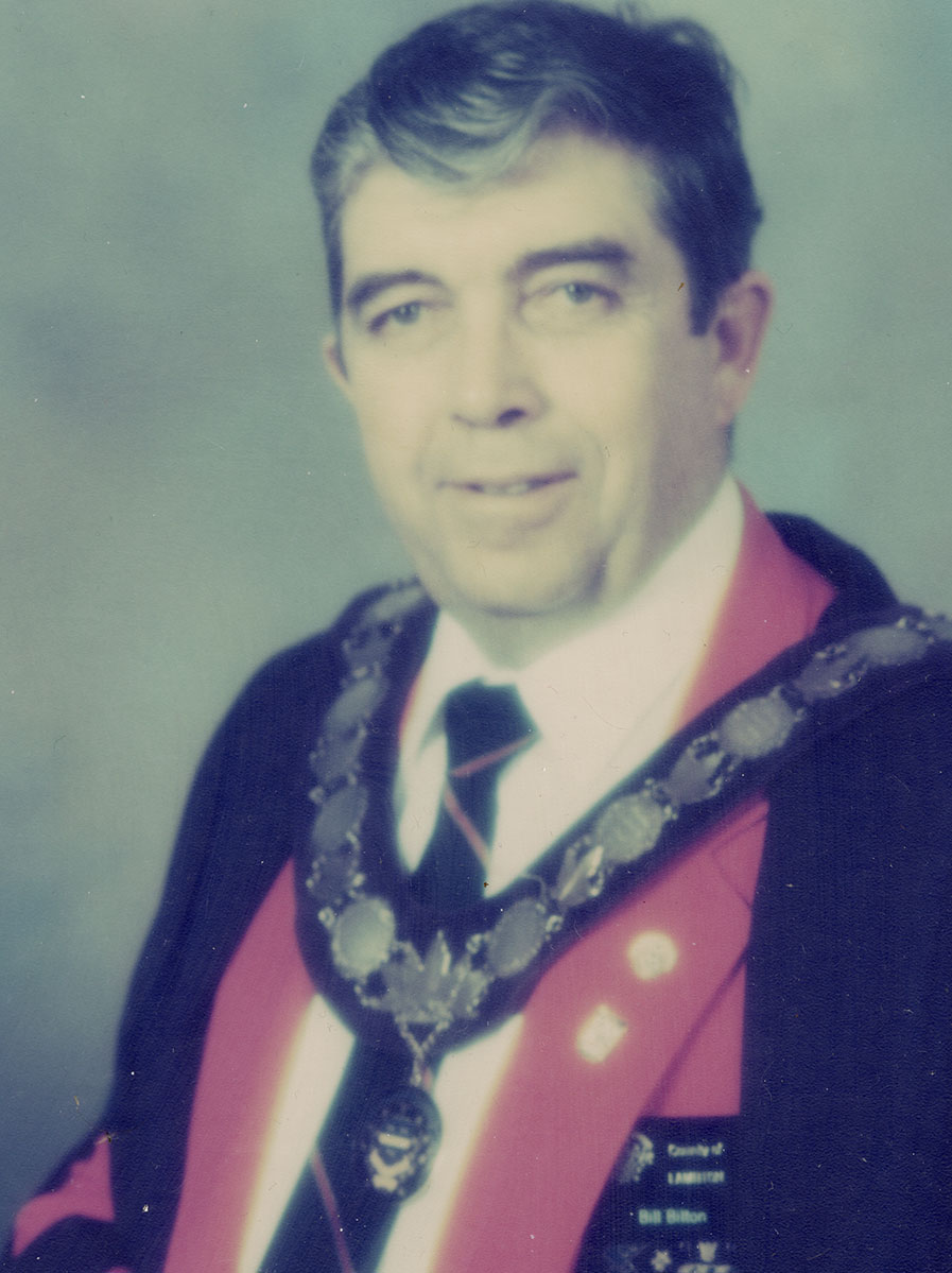 Photo of man in a suit and warden medal.