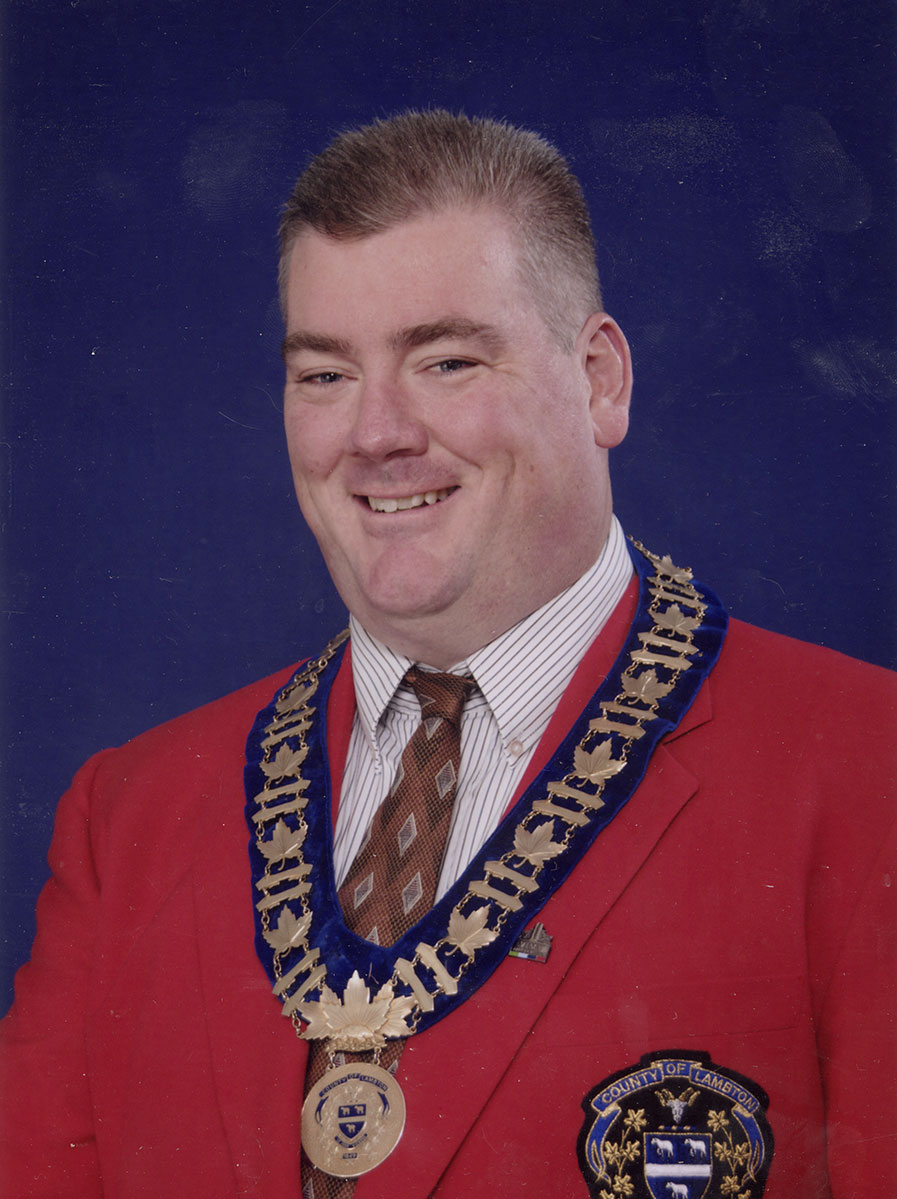 Photo of man in a suit and warden medal.