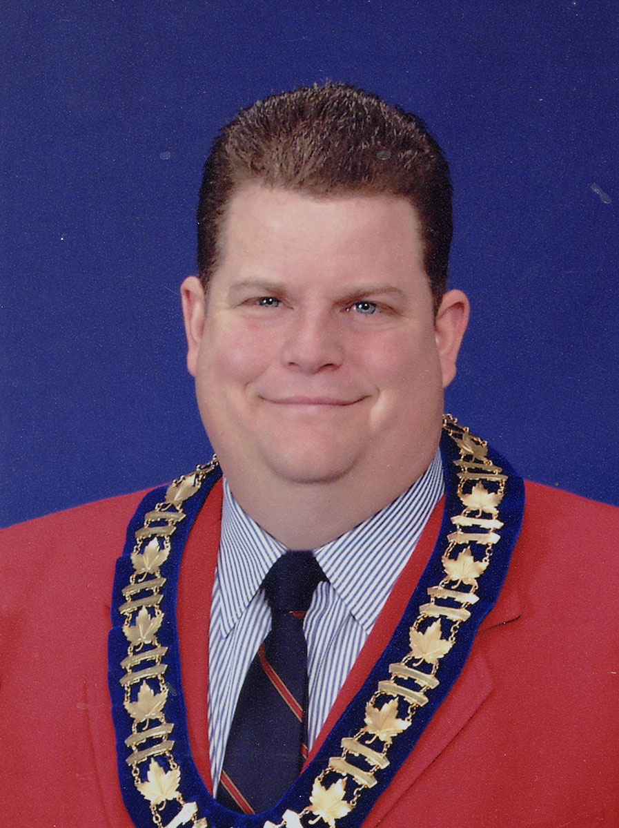 Photo of man in a suit and warden medal.