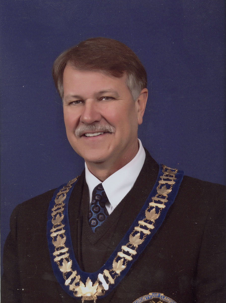 Photo of man in a suit and warden medal.
