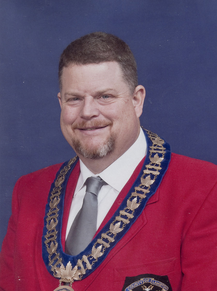 Photo of man in a suit and warden medal.