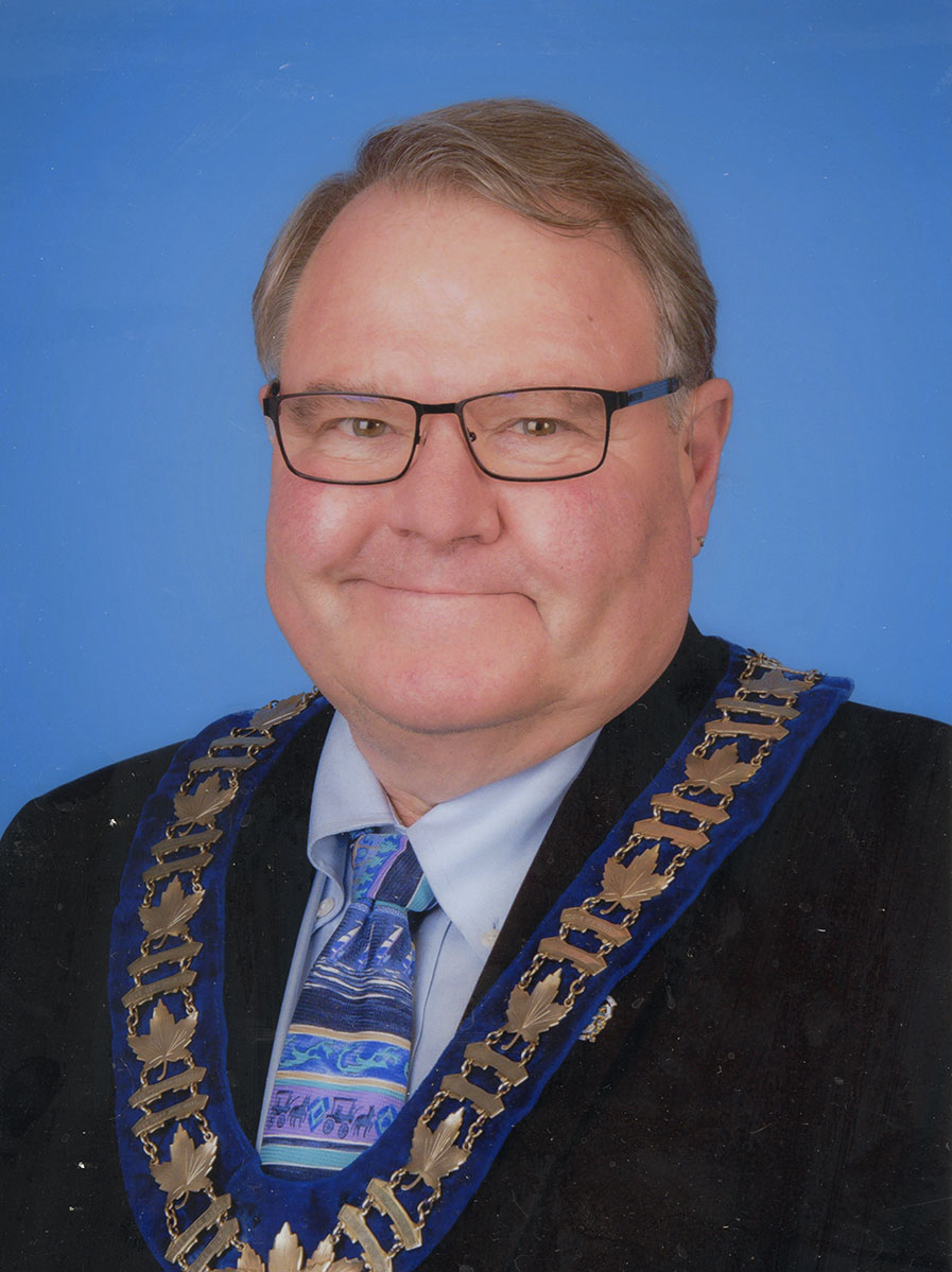 Photo of man in a suit and warden medal.