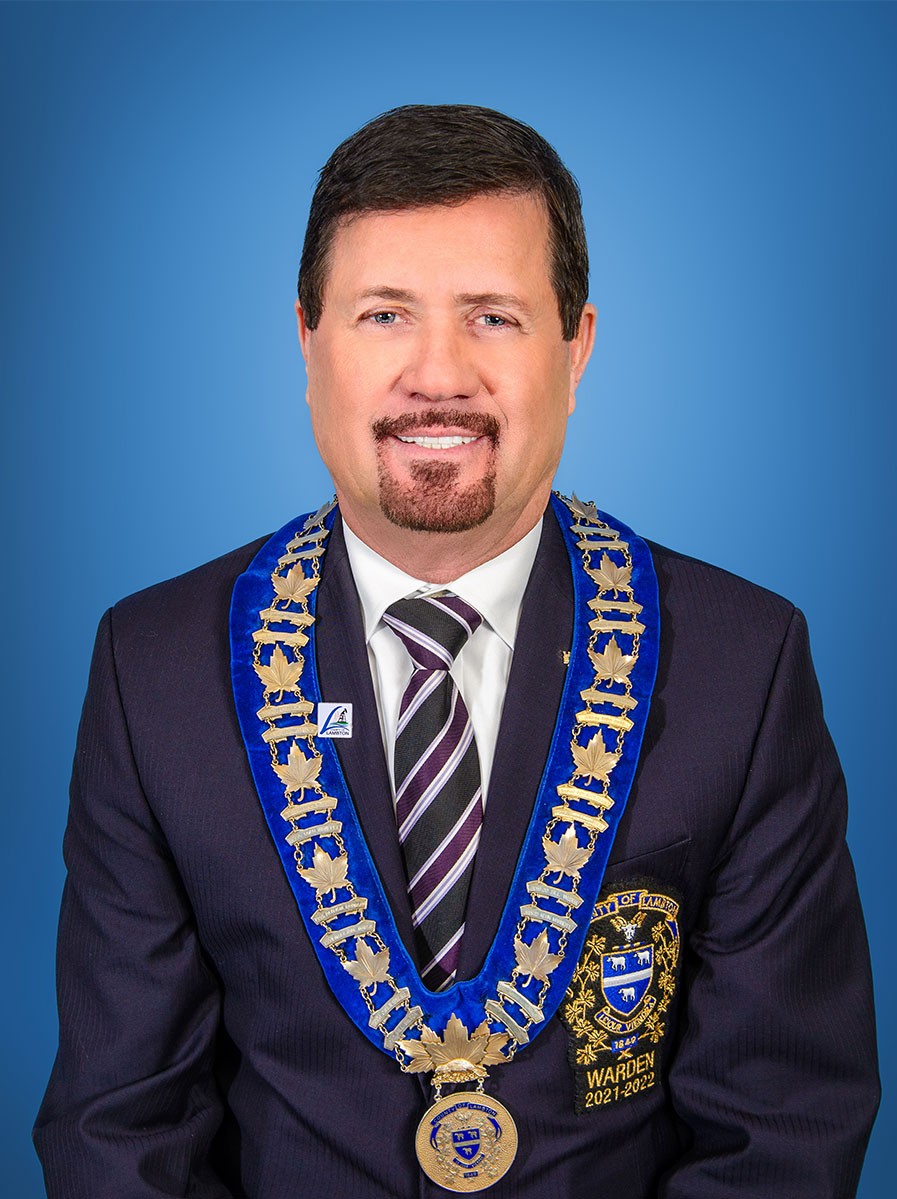 Photo of man in a suit and warden medal.