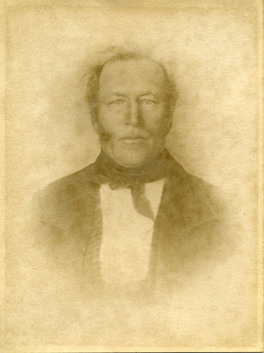 Historic image of an adult white male from the 1800s wearing a formal jacket and shirt.