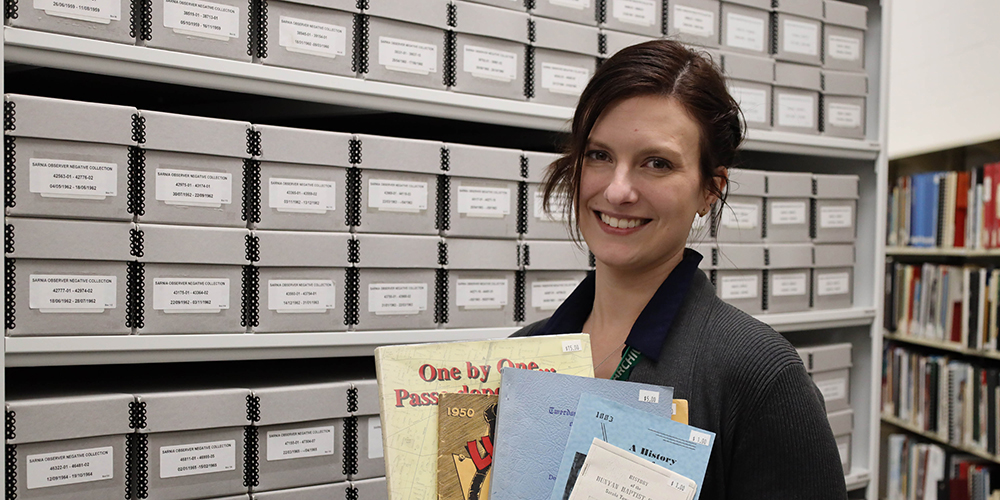 Archivist Nicole Aszalos holds examples of books for sale in the Leap Into History Book Sale