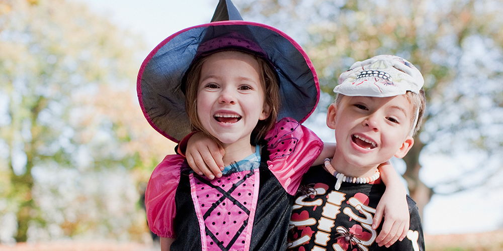 Two children dressed up for Halloween, smiling.