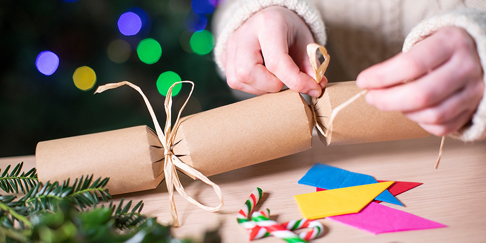 Child's hands hold a handmade paper Christmas cracker