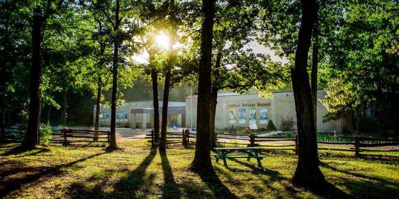 Exterior of Lambton Heritage Museum through trees with sun shining