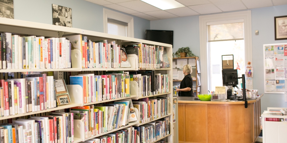 Shelf filled with books in front of a library circulation desk