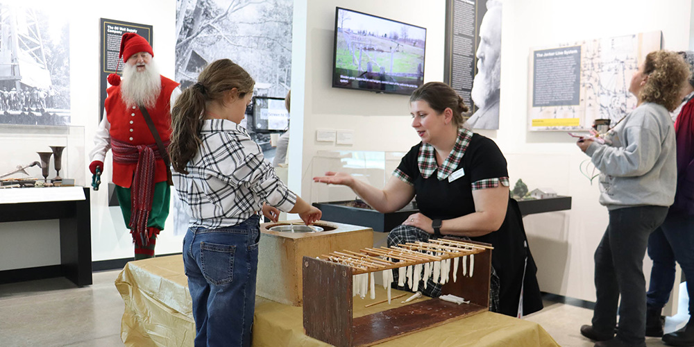 Oil Museum staff instruct a child on candle-dipping at Holiday Open House