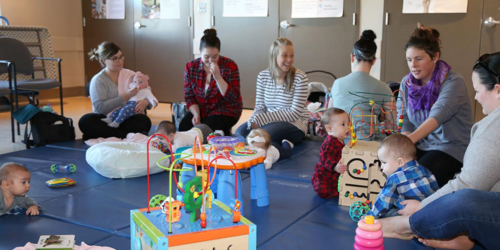 Mothers sitting on the floor with their babies and children's toys