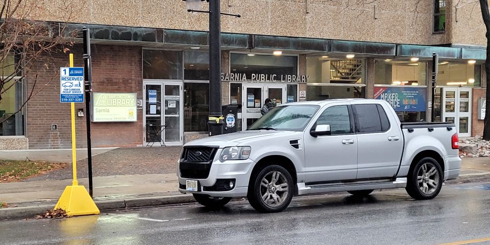 Pickup truck waiting for curbside pickup service outside of the Sarnia Library