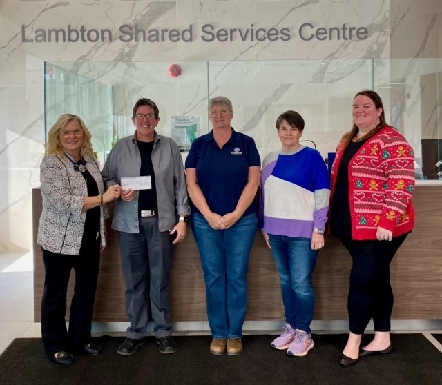 Group of people standing in front of the sevice desk at the Lambton Shared Services Centre for a cheque presentation