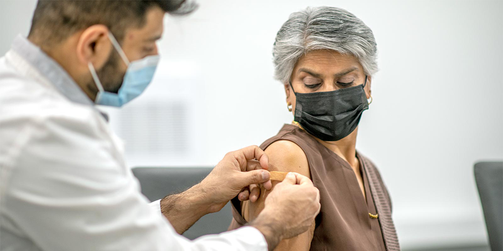 Woman has bandage placed on arm after receiving COVID-19 vaccine.