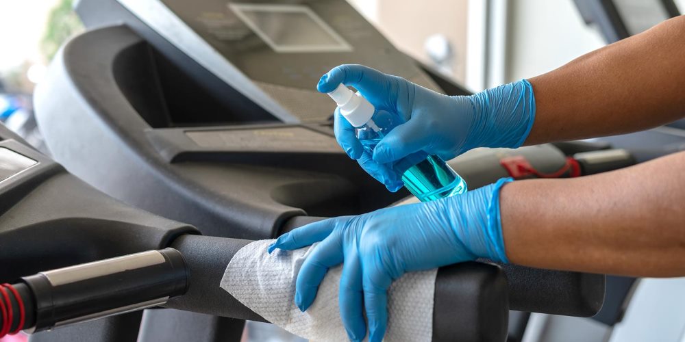 Person wearing gloved cleaning treadmill