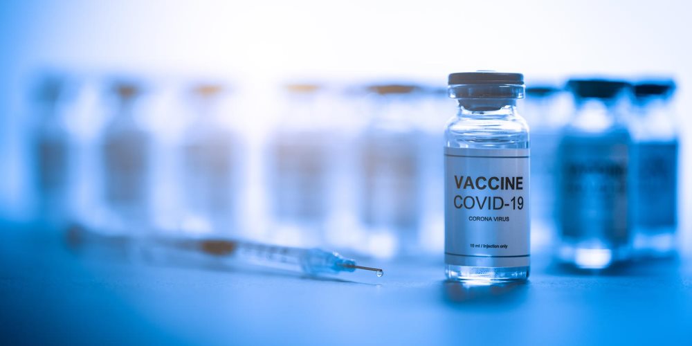 Vials of the COVID-19 vaccine with a syringe lying in front of them