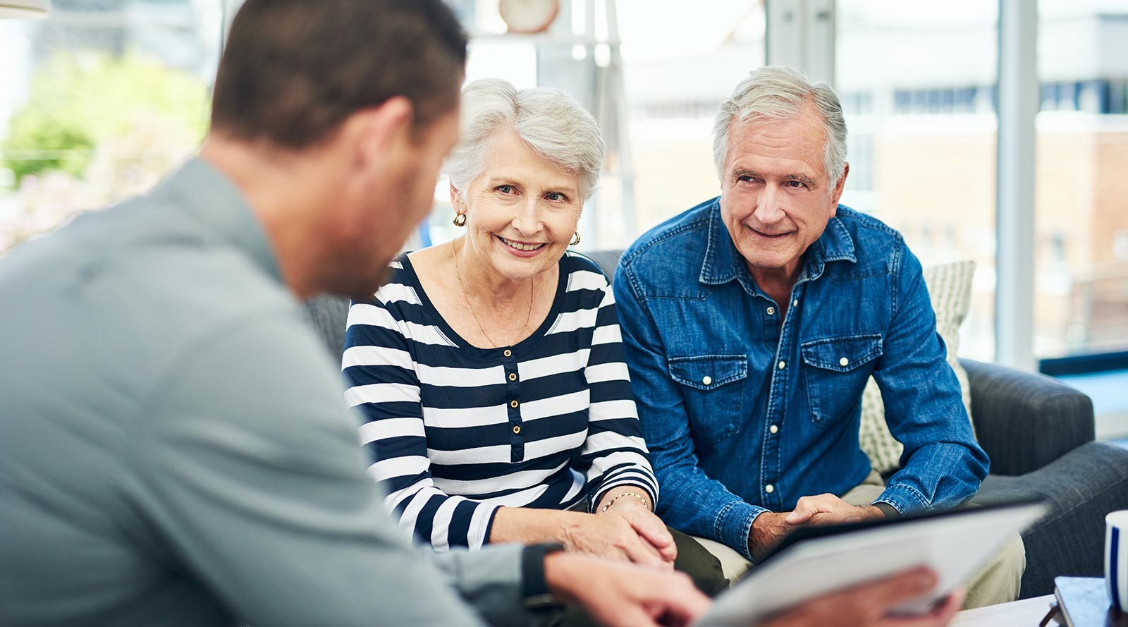 Elderly couple sitting on a couch speaking to someone