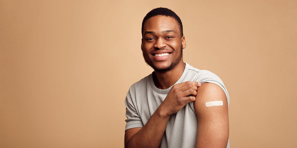 Man holding up t-shirt sleeve to show bandage on arm