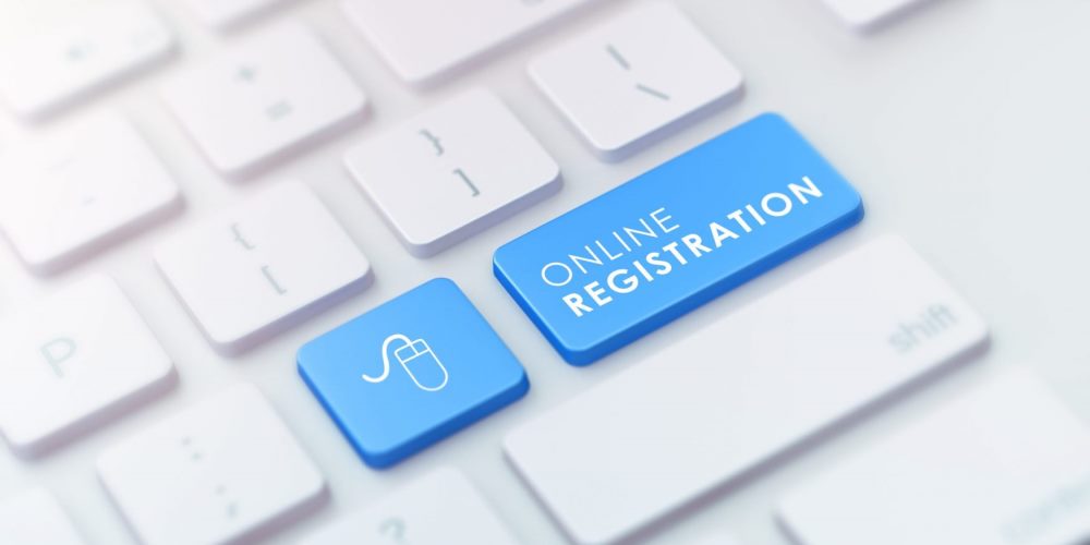 white computer keyboard with blue buttons with a computer mouse and "online registration" on them