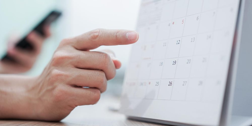 Person holding phone pointing at calendar