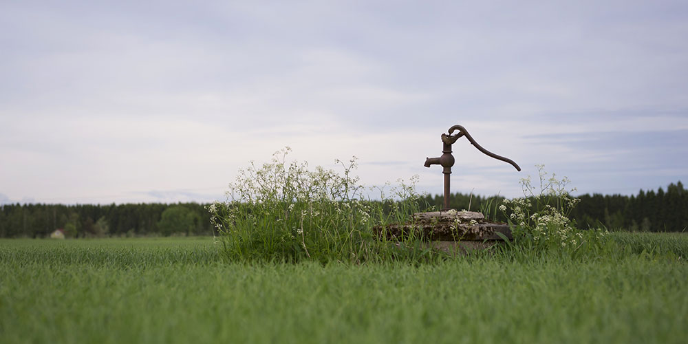 well hand pump in grassy field