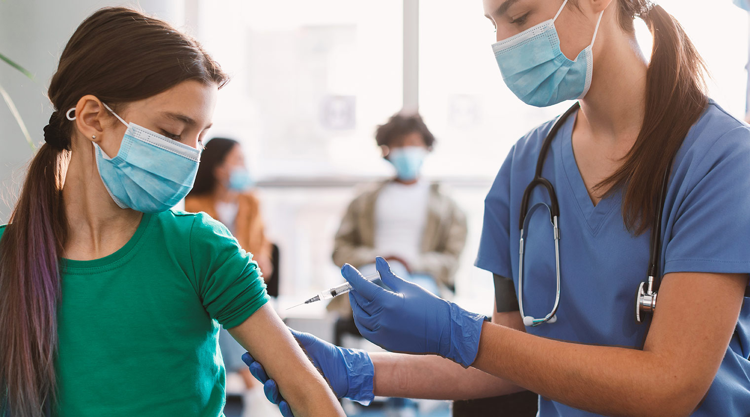 young girl receives vaccination from nurse