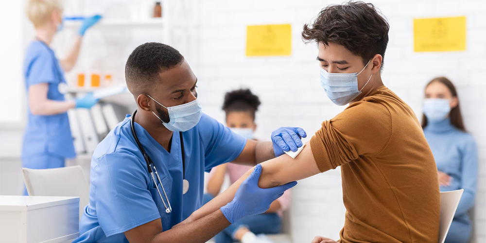 Young man receives vaccination from medical professional.